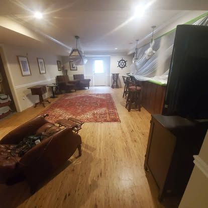 A living room with hardwood floors , a couch , chairs , and a rug.