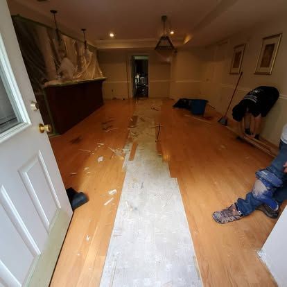 A man is painting a wooden floor in a room.