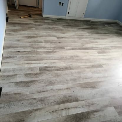 A room with a wooden floor and a hammer on the floor.