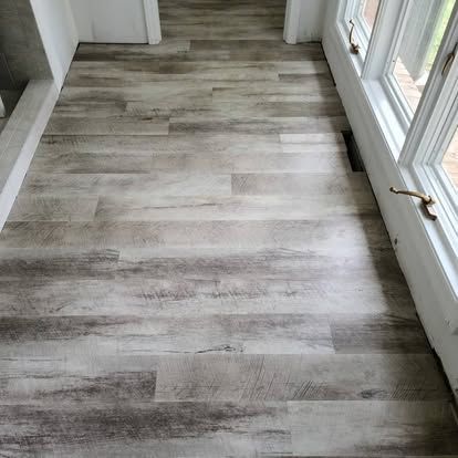 A hallway with a wooden floor and a lot of windows.