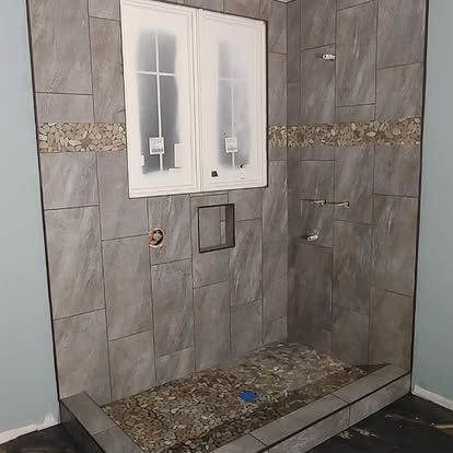 A bathroom with a walk in shower and a window.