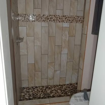 A bathroom with a walk in shower and a tiled wall.