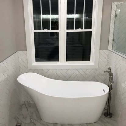 A white bathtub is sitting in a bathroom next to a window.