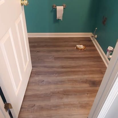 A bathroom with hardwood floors and a toilet paper holder on the wall.
