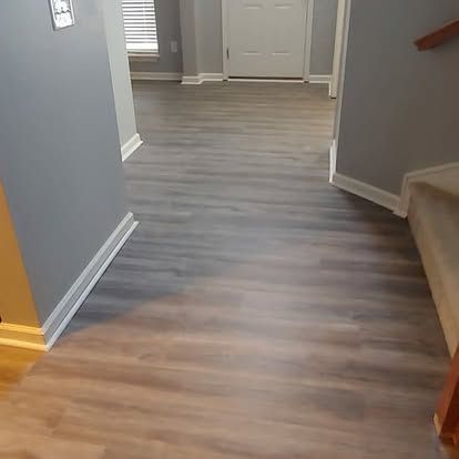 A hallway with hardwood floors and stairs in a house.