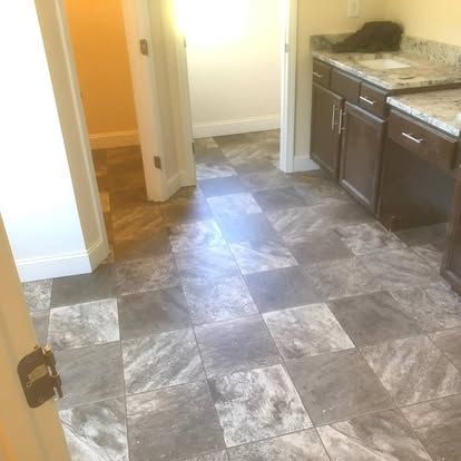 A kitchen with a tiled floor , cabinets , and a sink.