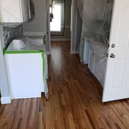 A kitchen with hardwood floors and white cabinets is being painted.