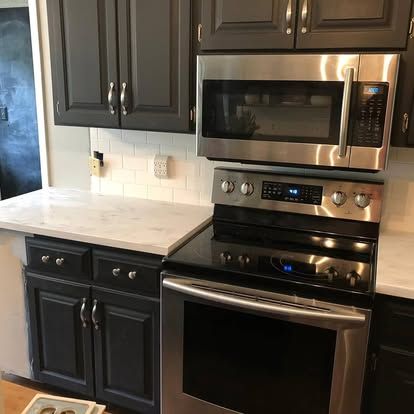 A kitchen with stainless steel appliances and black cabinets