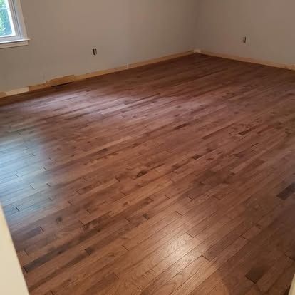A large empty room with hardwood floors and a window.