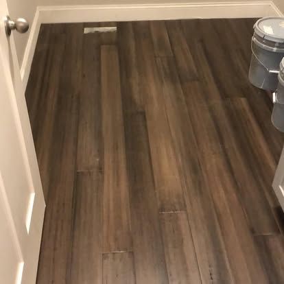 A bathroom with a wooden floor and two trash cans.