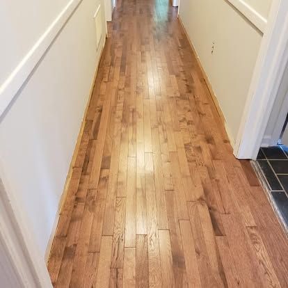 A long hallway with hardwood floors and white walls.