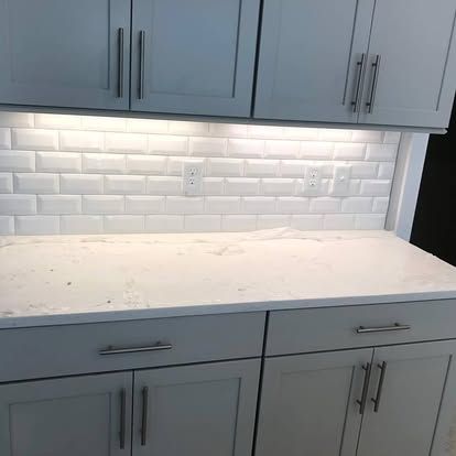 A kitchen with white cabinets and a white counter top.