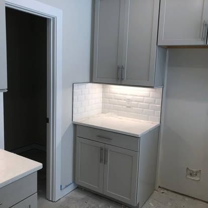 A kitchen with white cabinets and a white counter top.