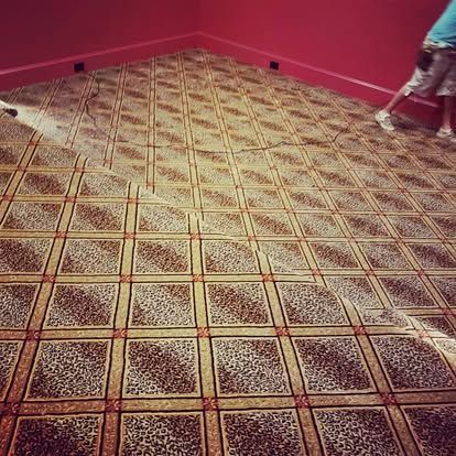 A person is vacuuming a carpeted floor in a room.