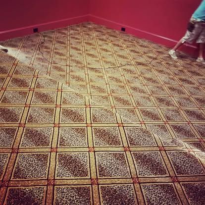 A person is vacuuming a carpeted floor in a room.