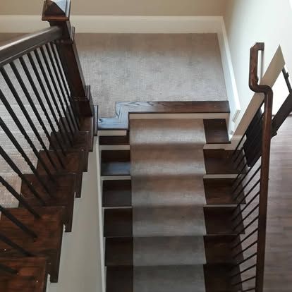 A wooden staircase with a metal railing and a carpeted staircase