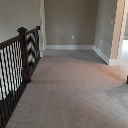 A hallway with a wooden railing and a carpeted floor in a house.