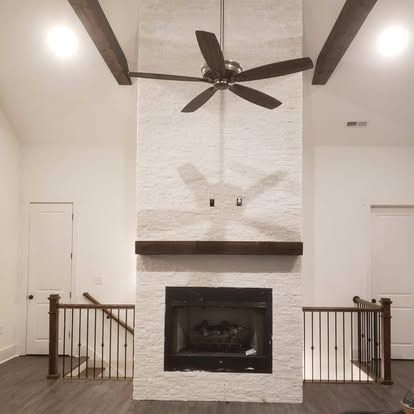 A living room with a fireplace and a ceiling fan.