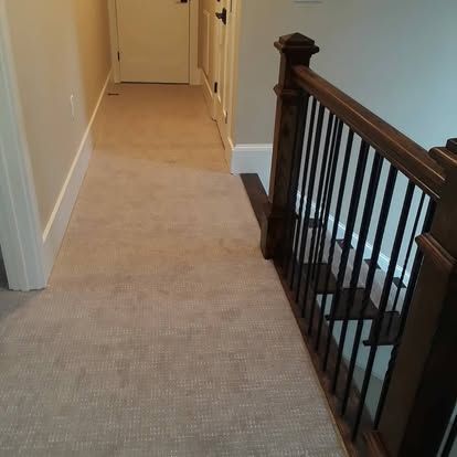 A hallway with a wooden railing and stairs in a house.