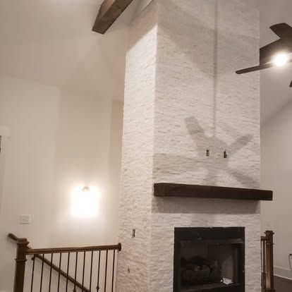 A living room with a fireplace and a ceiling fan.