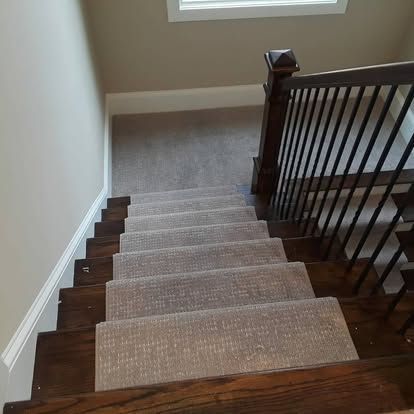 A staircase with a carpeted staircase and a wooden railing.