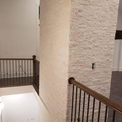 A staircase with a wooden railing and a brick wall.