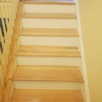 A wooden staircase with white steps and a wooden railing.
