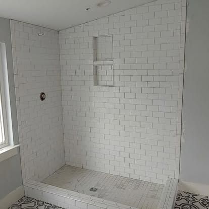 A bathroom with white brick walls and a walk in shower.