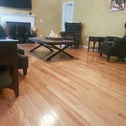 A living room with hardwood floors , a coffee table , chairs , and a fireplace.