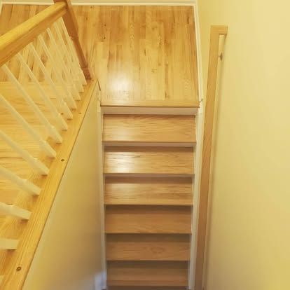 A wooden staircase with a white railing and wooden steps in a room.