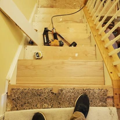 A person is standing on the bottom of a wooden staircase.