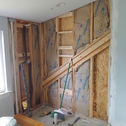 A room with a ladder and a broom under a staircase.