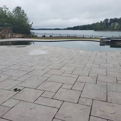 A patio with a swimming pool and a lake in the background