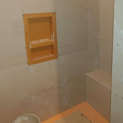 A bathroom with a shower stall and a shelf in the wall.