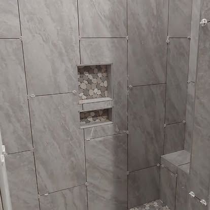 A bathroom with a walk in shower and a shelf in the wall.