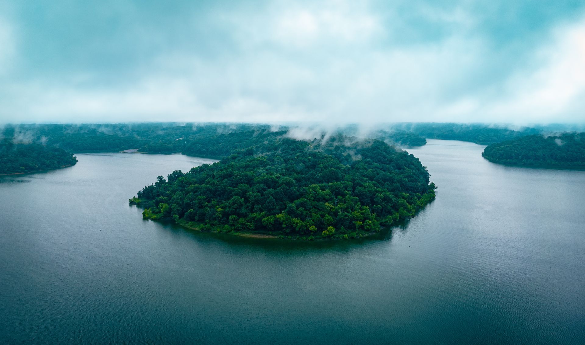an aerial view of a small island in the middle of a lake surrounded by trees .