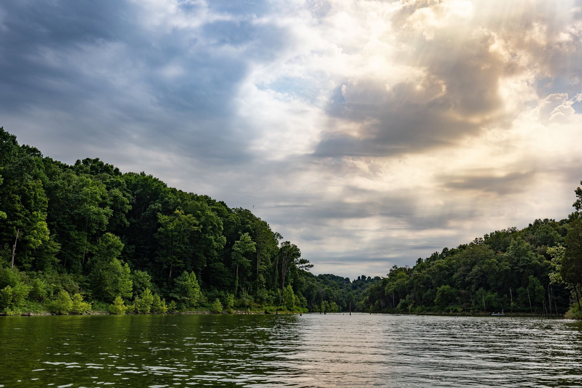a lake surrounded by trees on a cloudy day