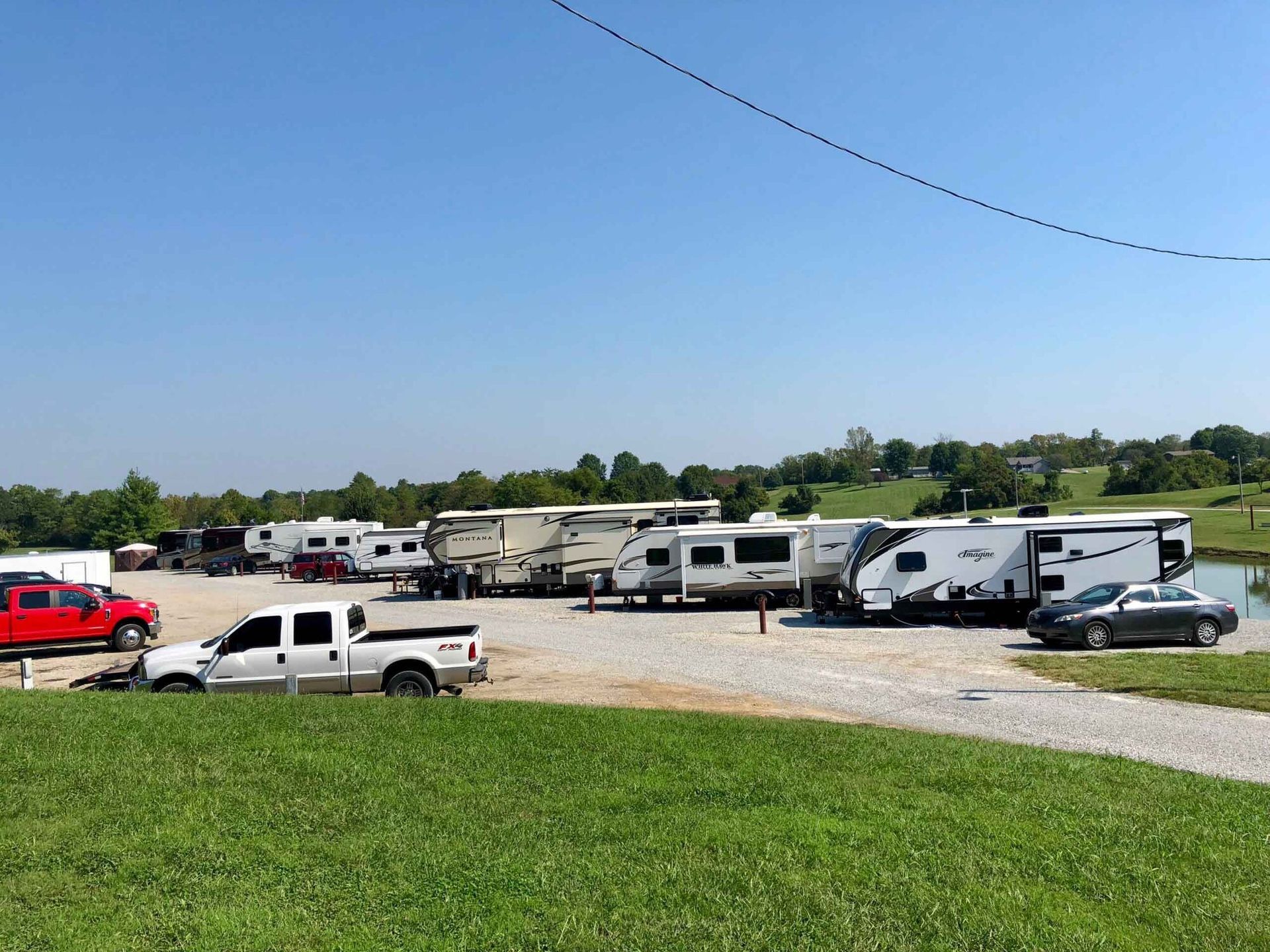 a row of rv 's are parked in a grassy area .