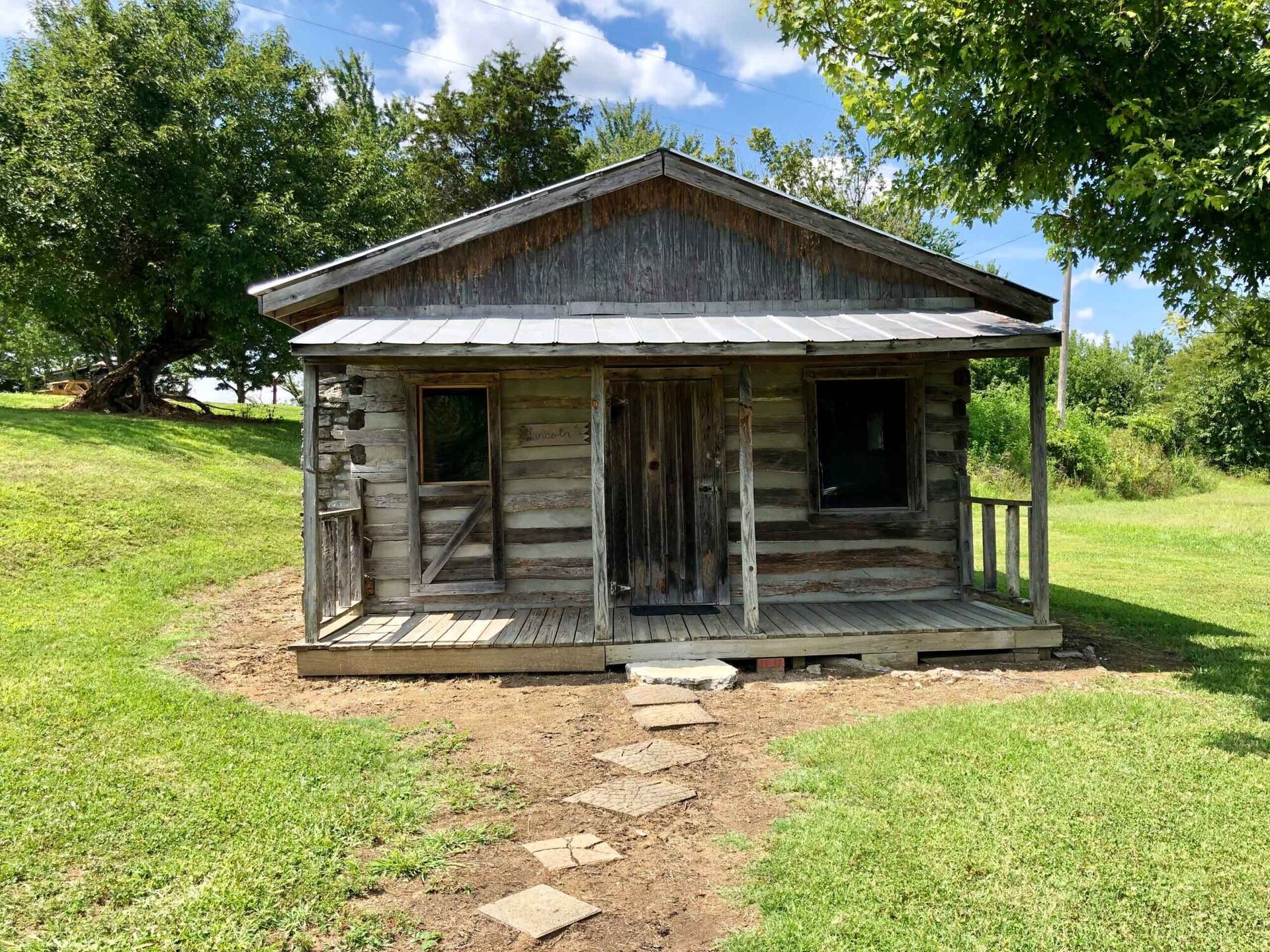 a small log cabin is sitting in the middle of a grassy field .