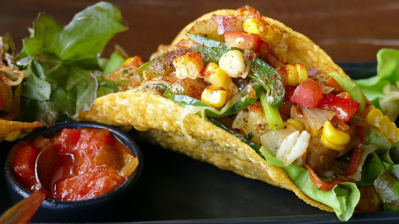a close up of a taco on a plate with salsa and a spoon .