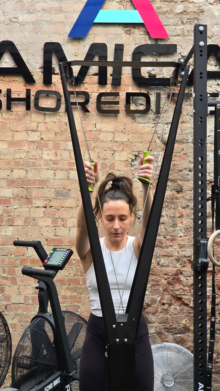 A woman is standing on a machine in front of a brick wall.