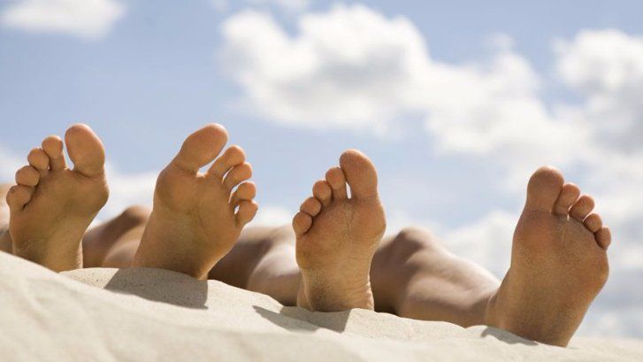 The feet of two people lying on the beach after a visit with a podiatrist in Cincinnati, OH