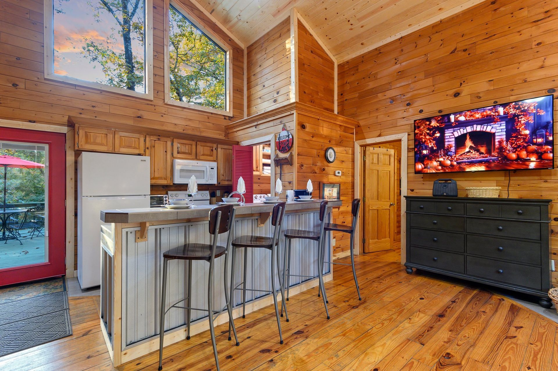 A kitchen in a log cabin with a large flat screen tv on the wall.