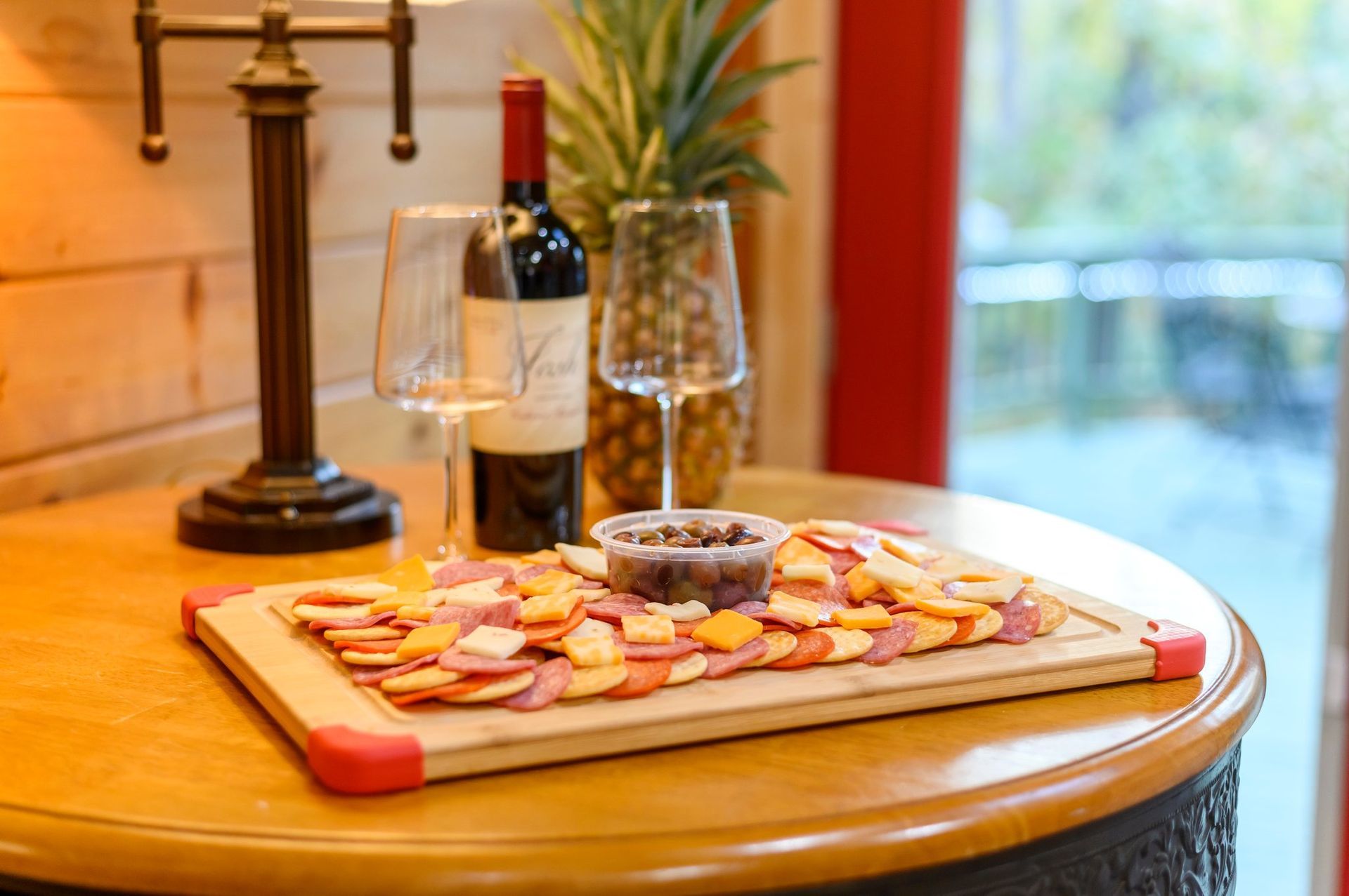 A cutting board with food and a bottle of wine on a table.