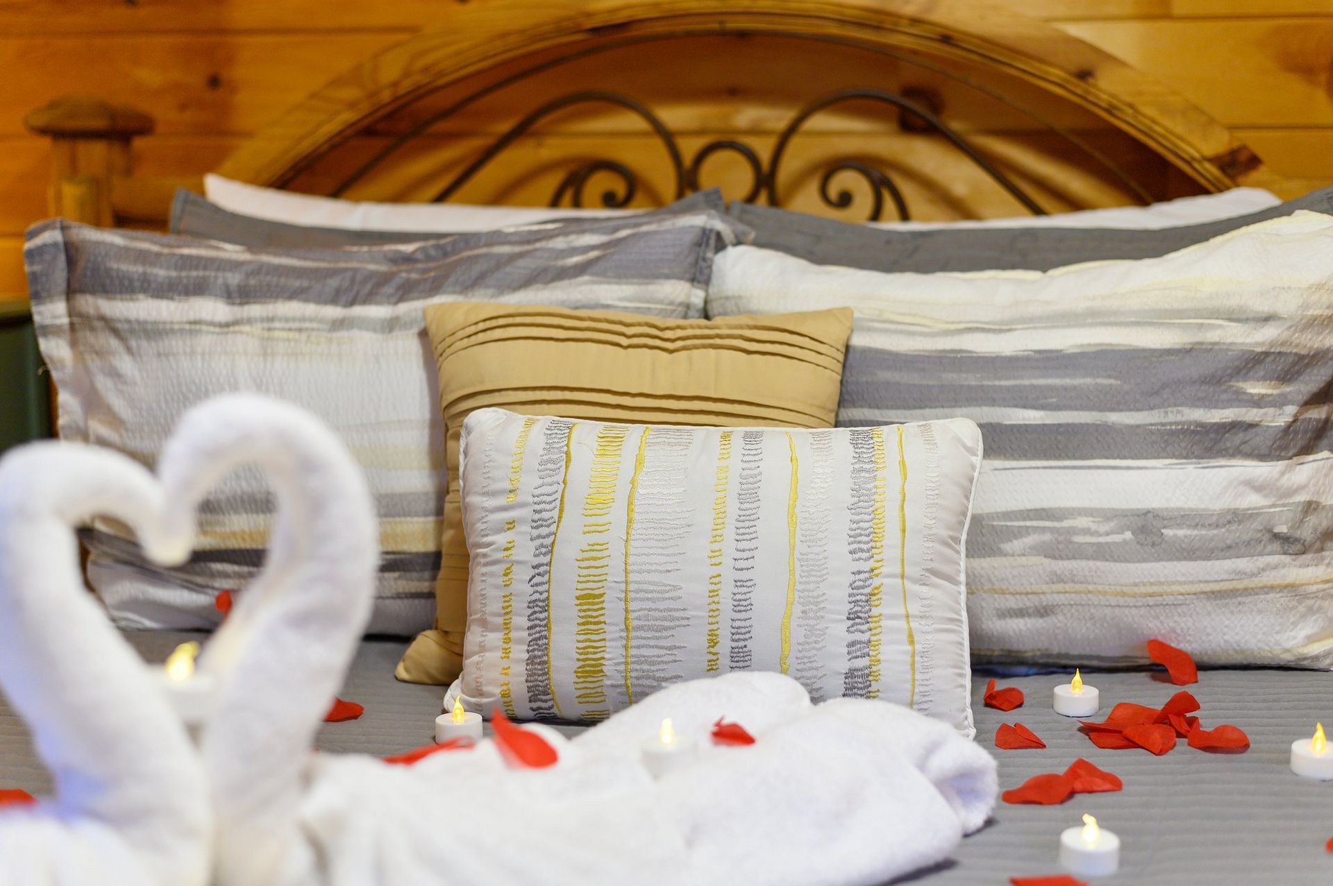 A bed with a heart shaped towel and candles on it.