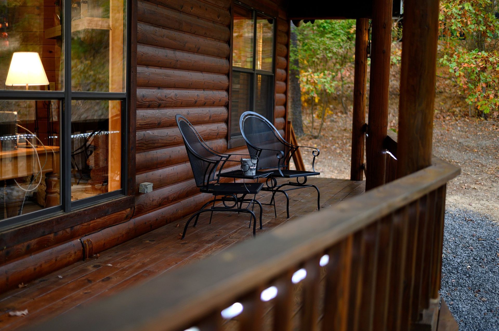 A wooden deck with chairs and a table in front of a log cabin.
