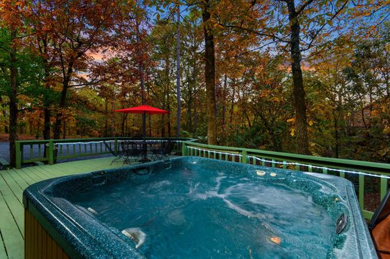 A hot tub is on a deck with trees in the background.