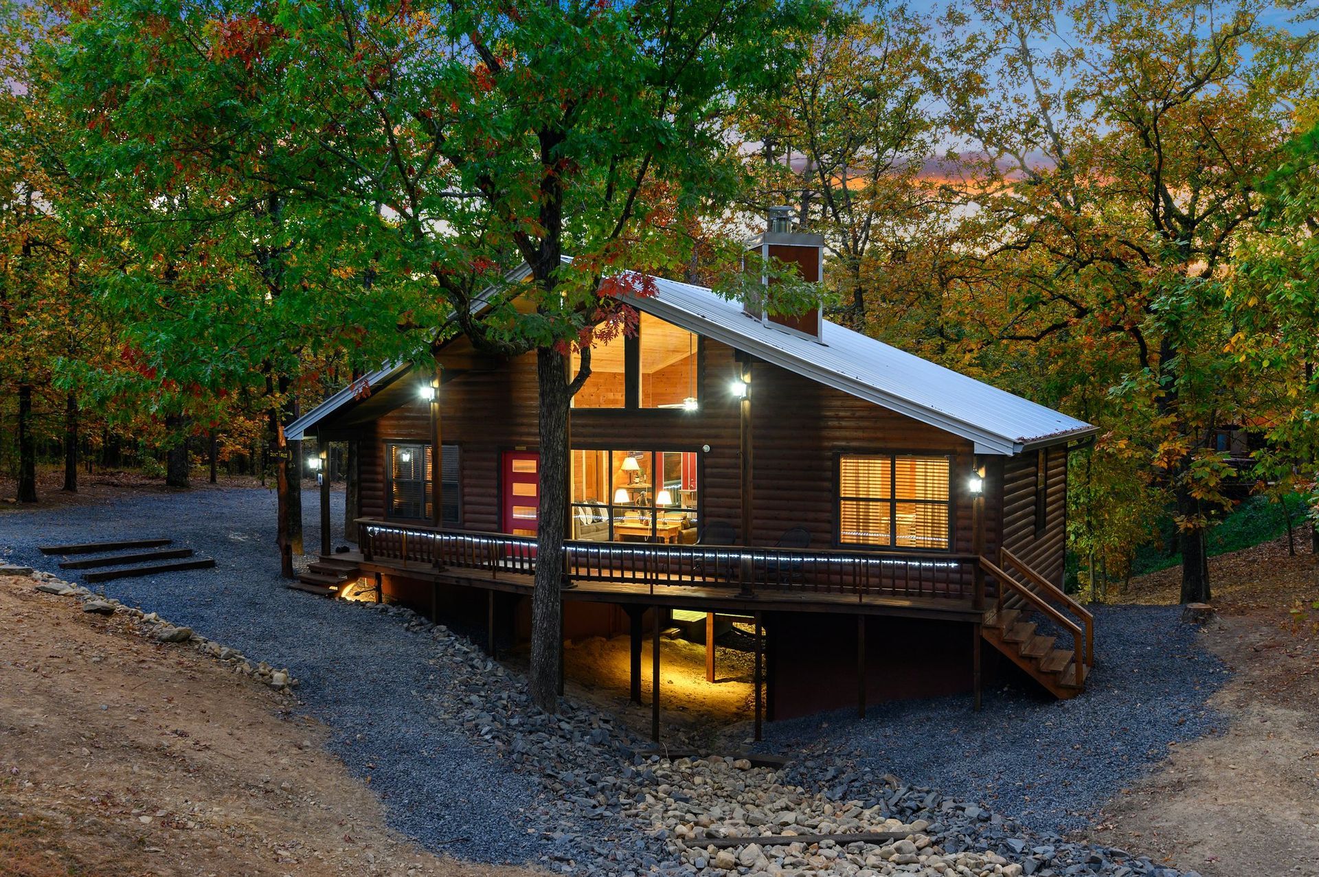 A log cabin is lit up at night in the middle of a forest.