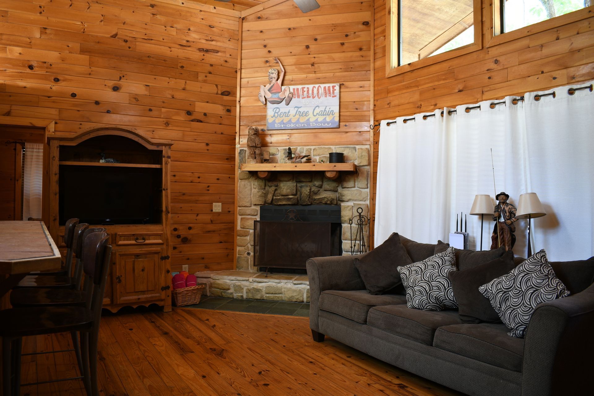 A living room in a log cabin with a couch , fireplace and television.