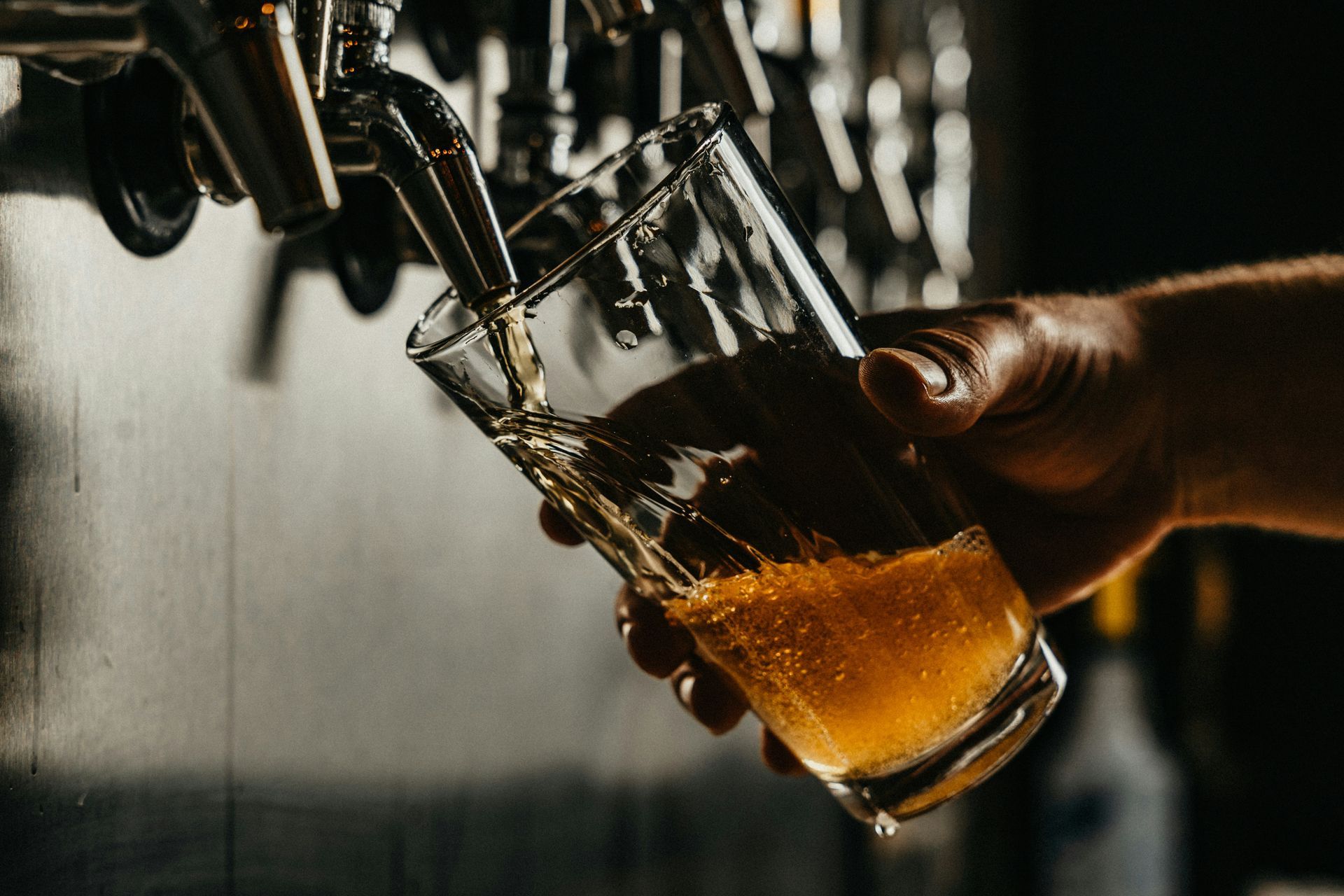A person is pouring beer into a glass from a tap.